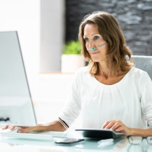 woman working at computer with nasal cannula on