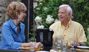 two people sitting at a table with one using an oxygen concentrator