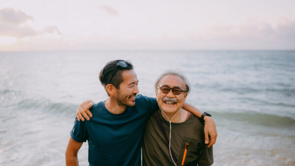 Japanese senior father and adult son having a good time on beach at sunset, Ishigaki Island, Okinawa, Japan